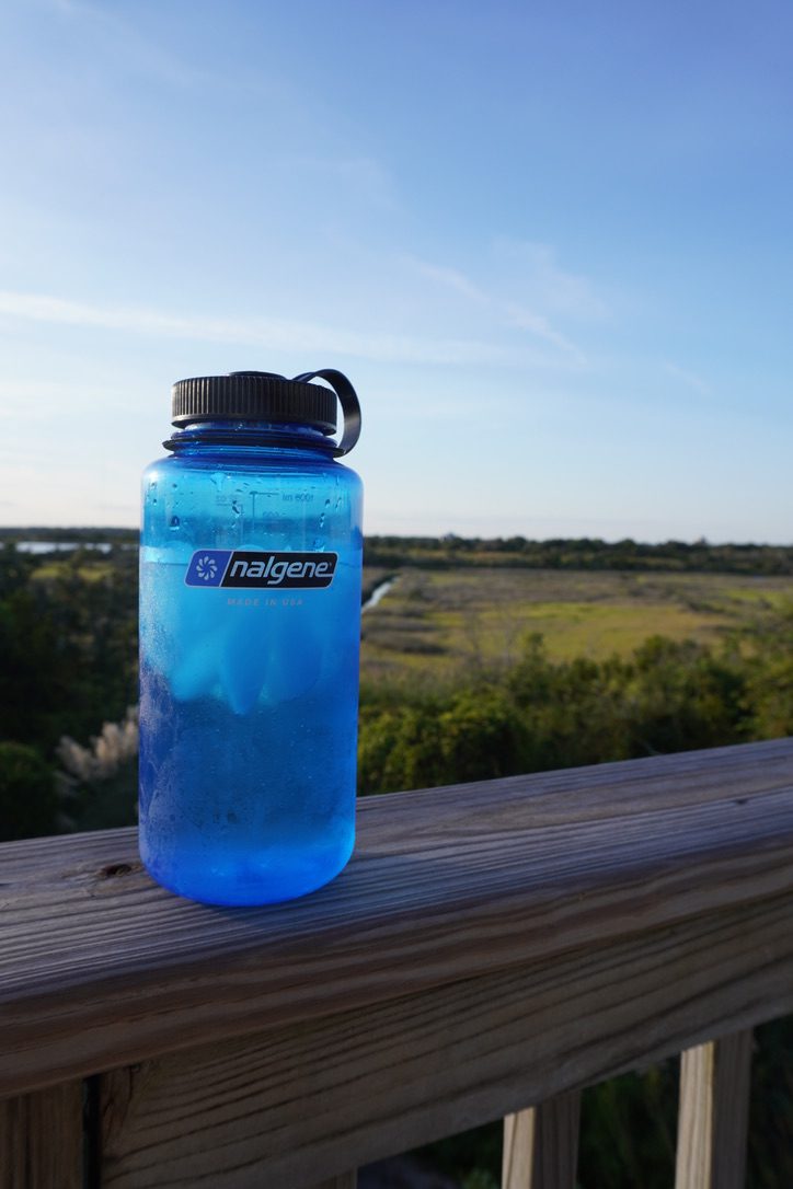 Nalgene wide mouth sits on a railing with a scenic view in the distance.